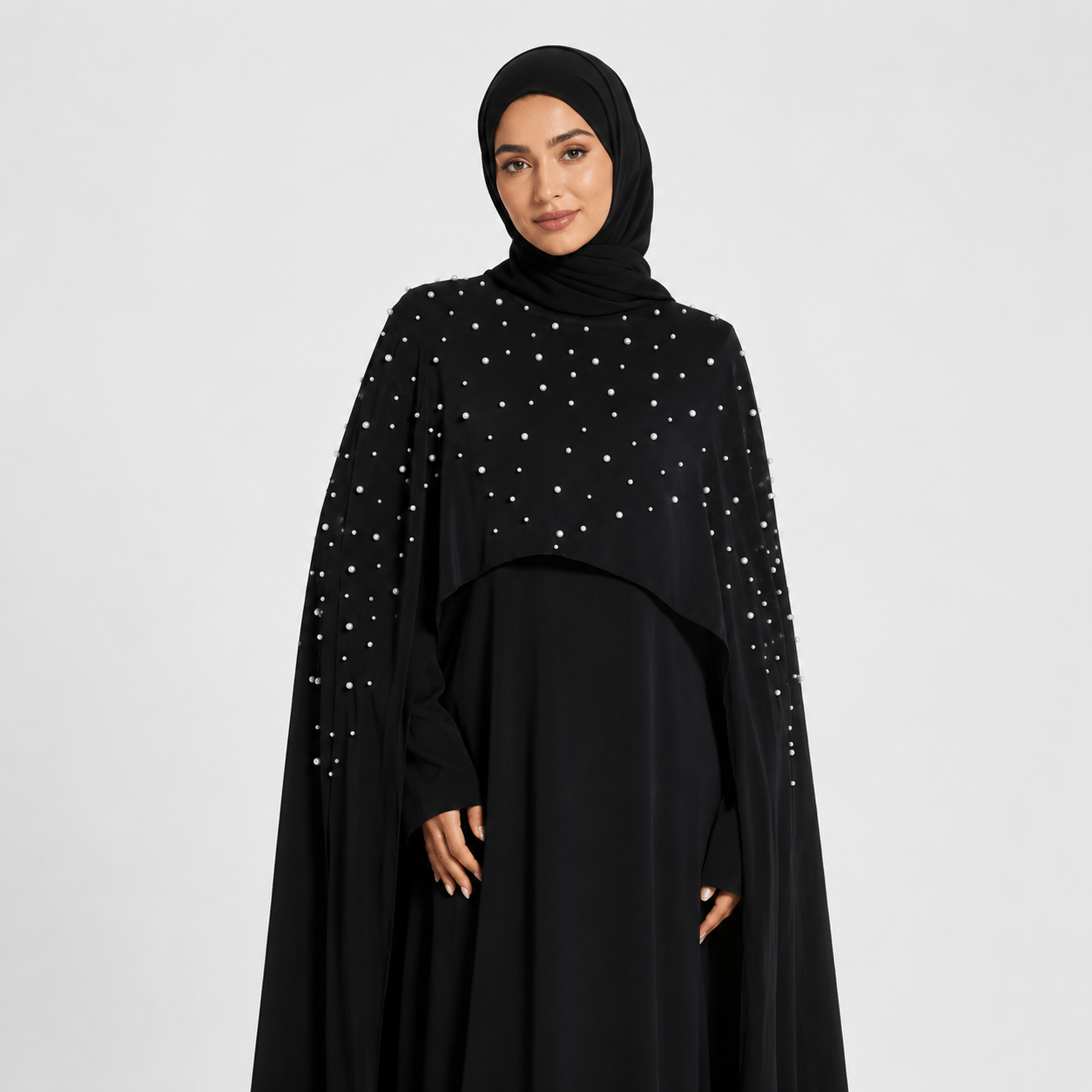 Woman wearing a black abaya with silver embellishments on a white background