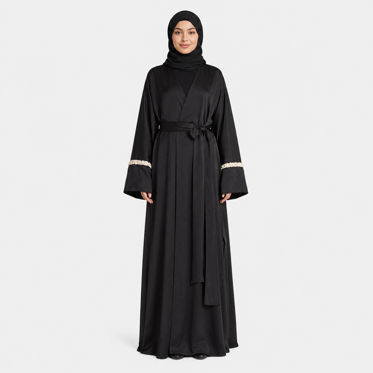 Woman wearing a black abaya with white trim on a white background