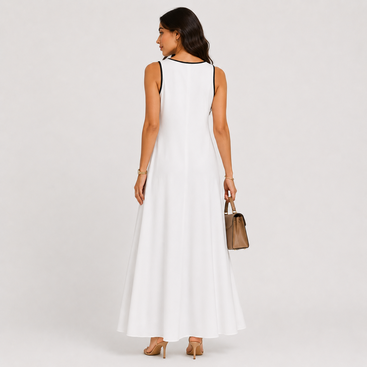 Woman wearing a white sleeveless dress holding a brown handbag on a plain background