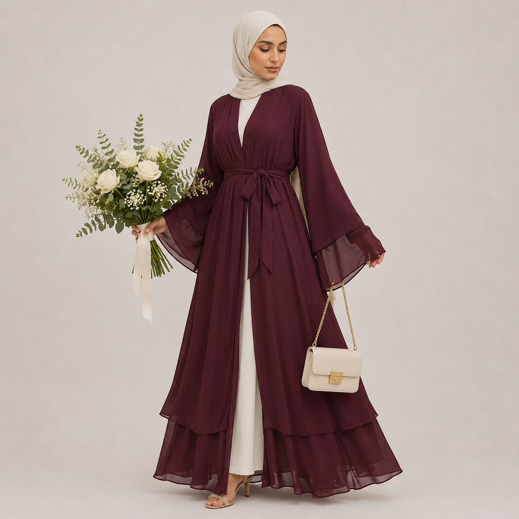 Woman in a burgundy abaya holding flowers and a handbag on a plain background