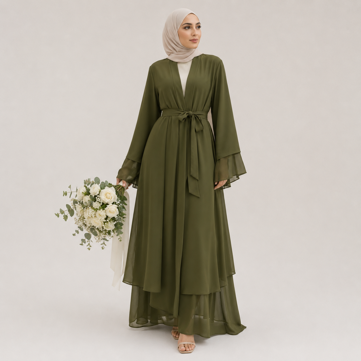 Woman wearing an olive green dress holding flowers on a plain background