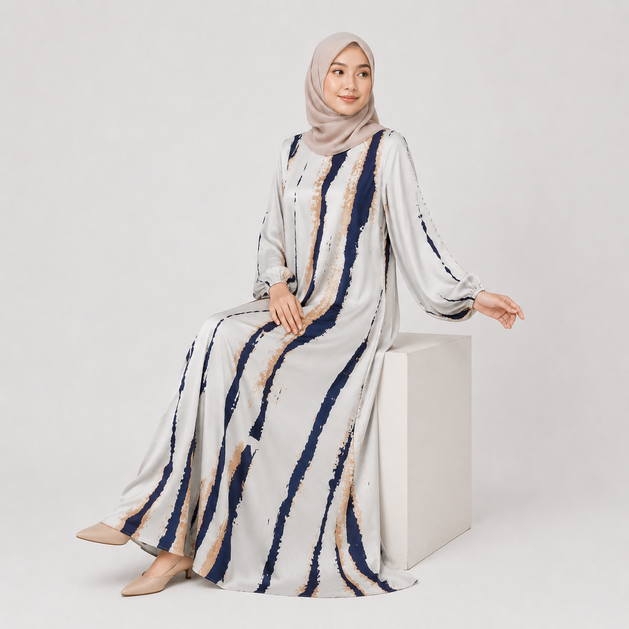 Woman wearing a long, patterned dress with a hijab on a white background