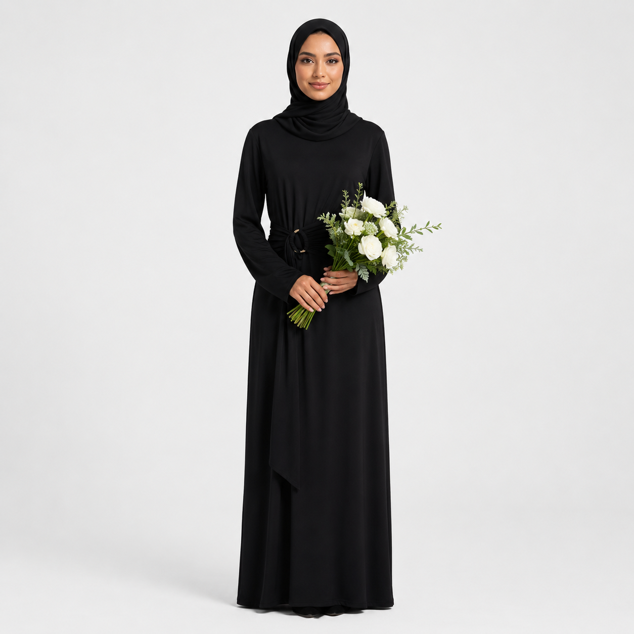 Woman wearing a black hijab and black dress holding flowers on a white background