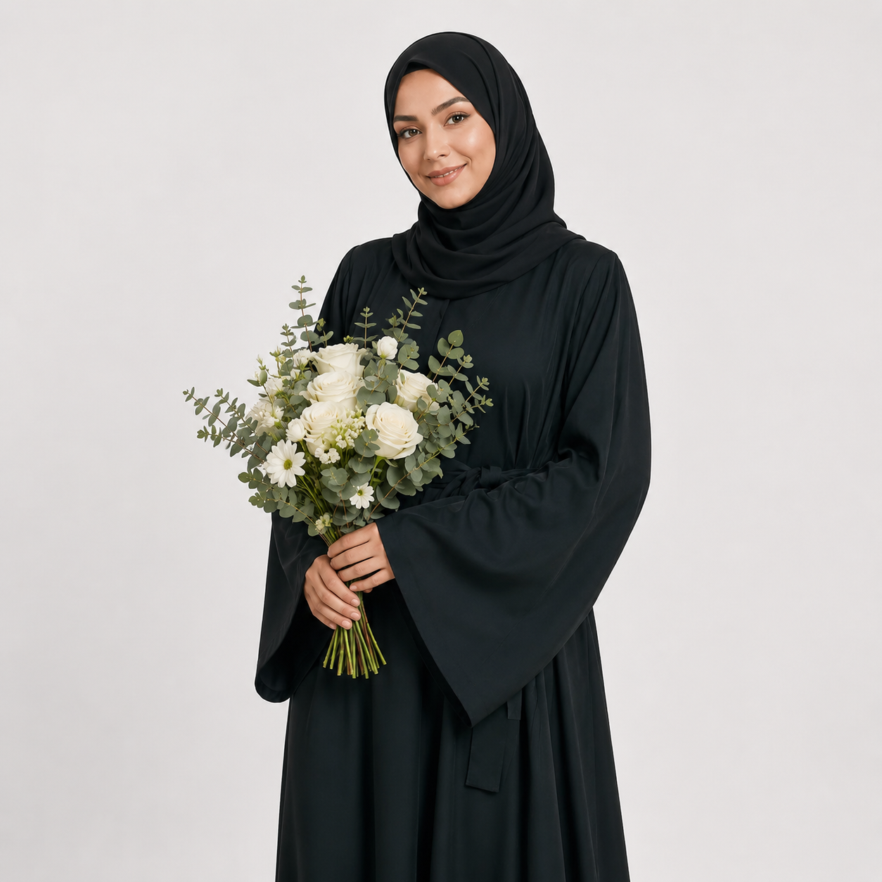 Woman in a black abaya holding a bouquet of flowers against a white background