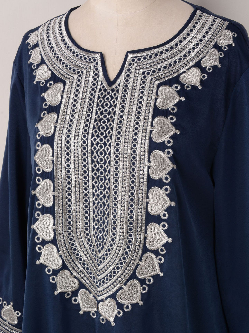 Navy blue garment with intricate white embroidery on a mannequin