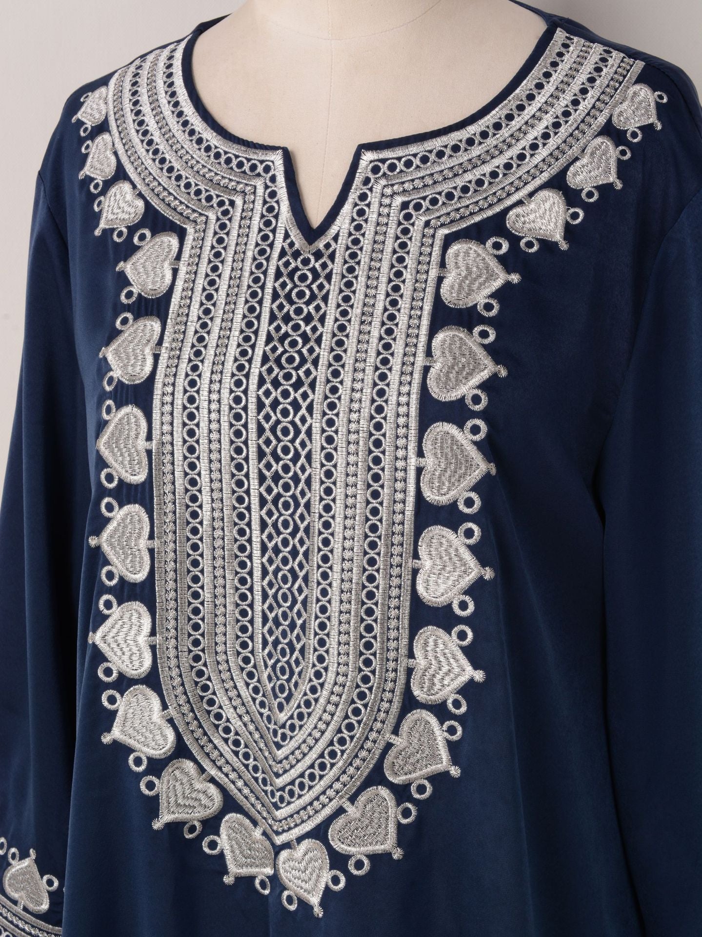 Navy blue garment with intricate white embroidery on a mannequin