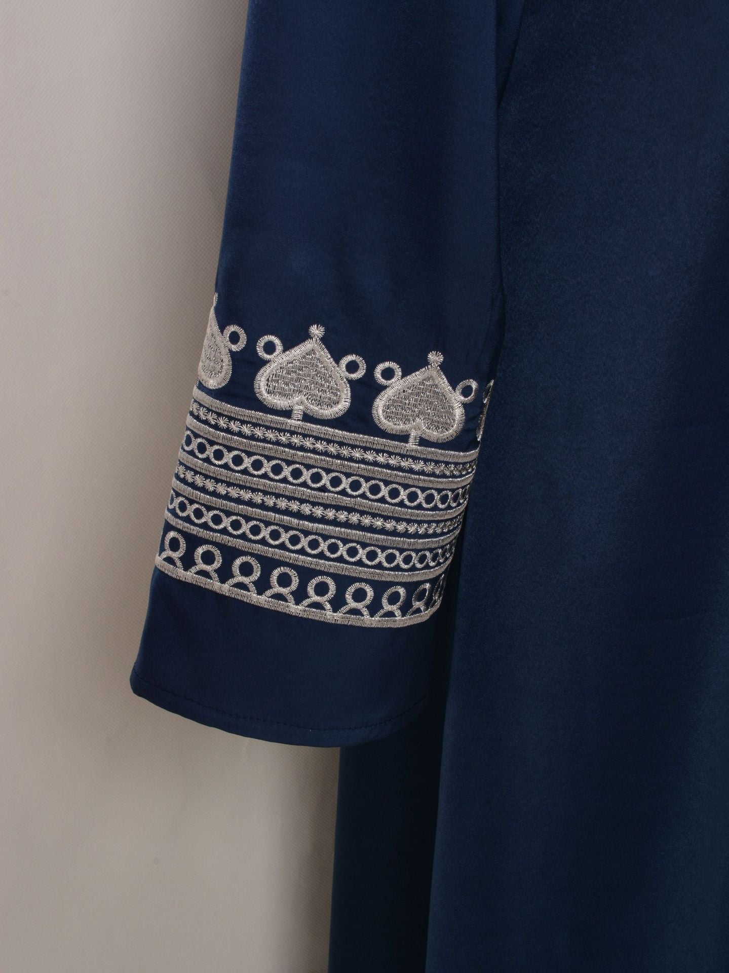 Navy blue garment with intricate white embroidery on a mannequin