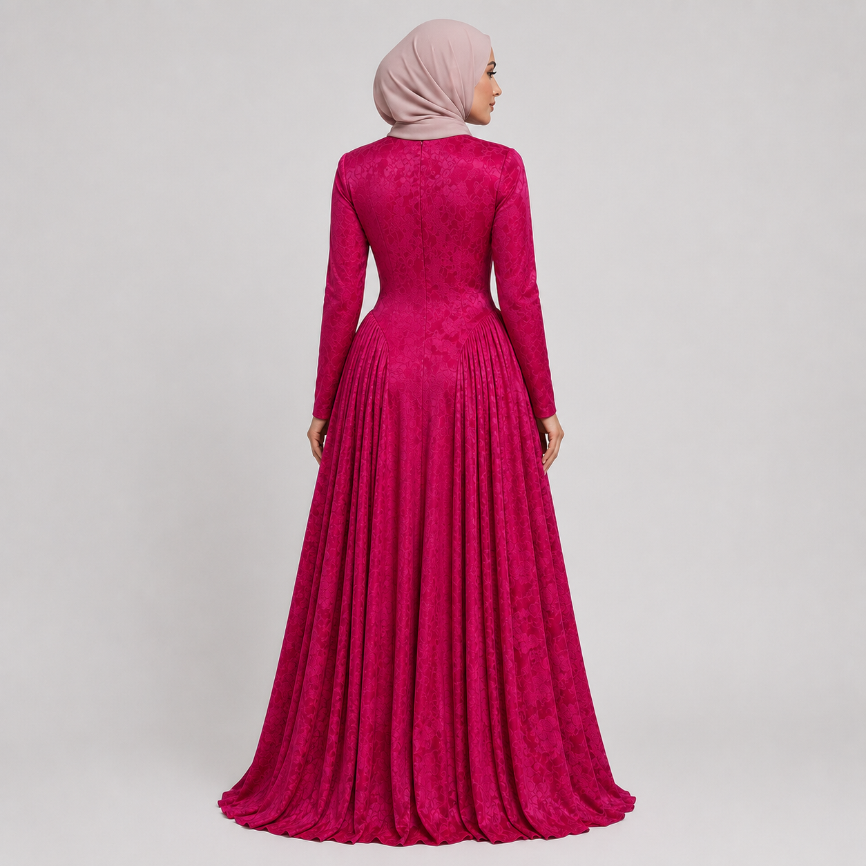 Woman wearing a long pink dress with a matching hijab on a light gray background