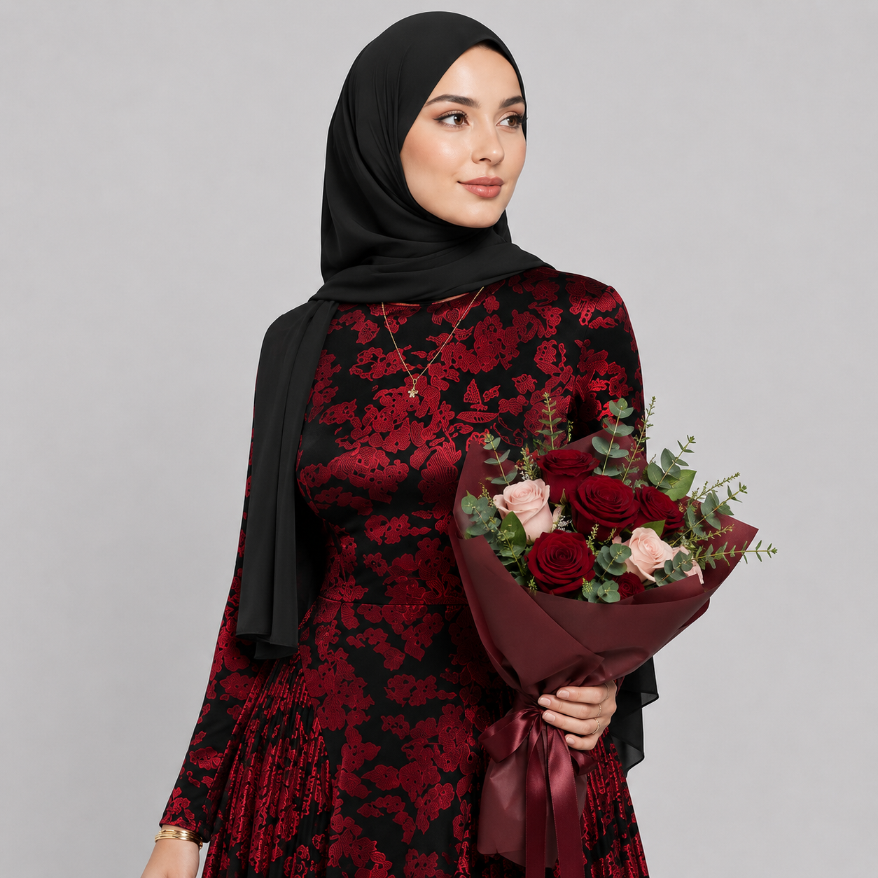 Woman in a red and black floral dress holding a bouquet of flowers against a gray background