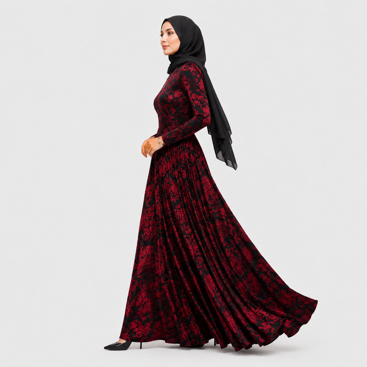 Woman wearing a red and black floral dress with a hijab on a light gray background