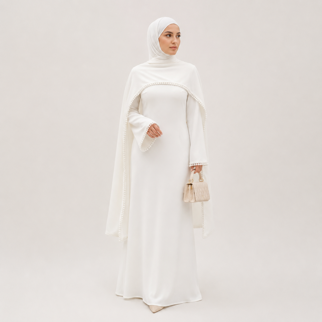 Woman wearing a white abaya with a matching hijab on a light gray background