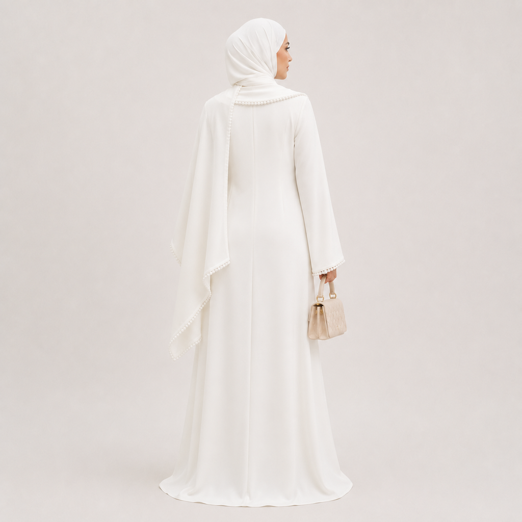 Woman wearing a white abaya and hijab against a light gray background