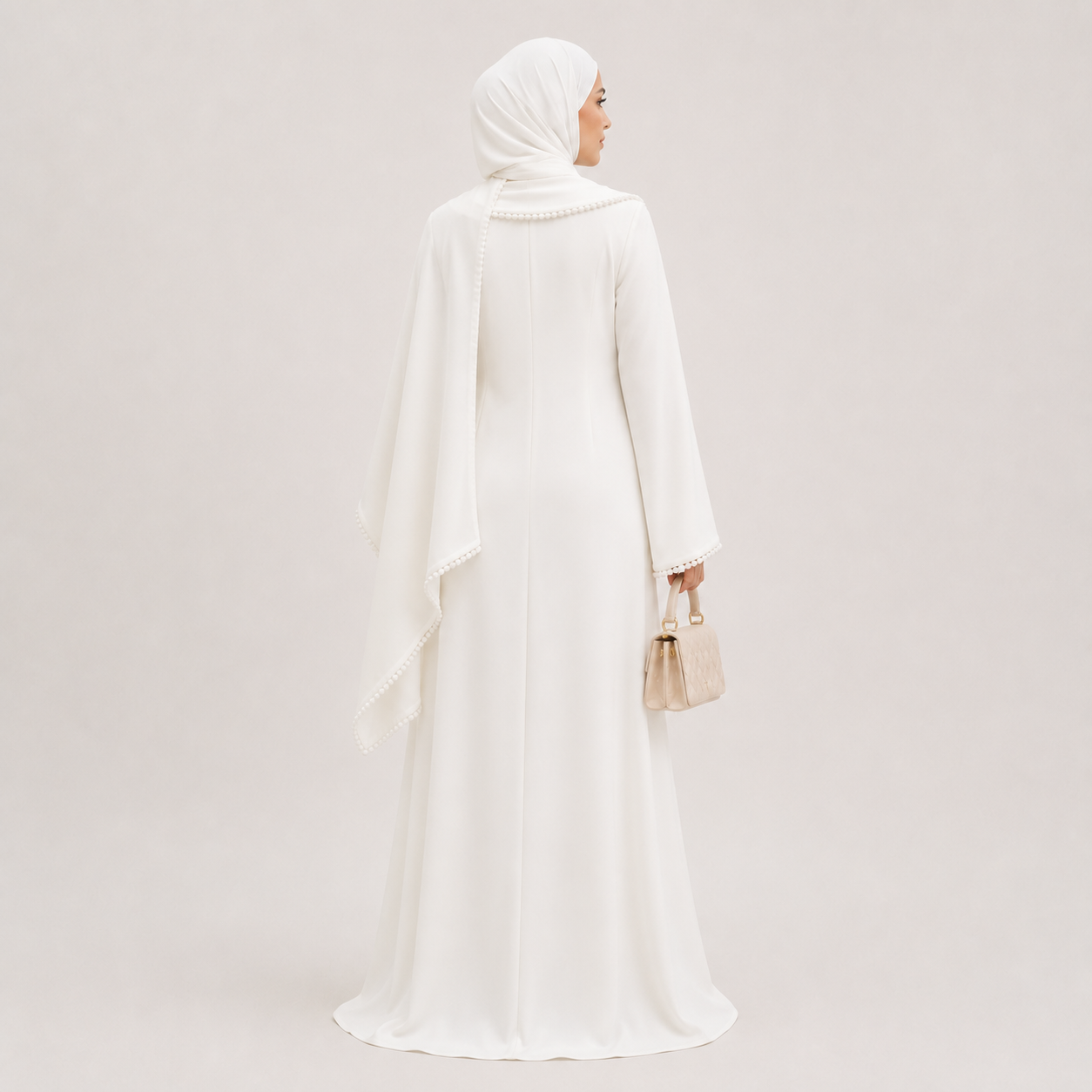 Woman wearing a white abaya and hijab against a light gray background