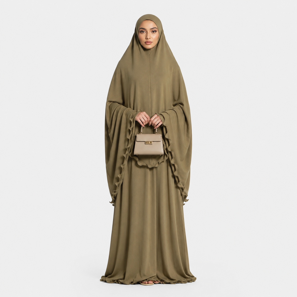 Woman wearing a long olive green dress holding a beige handbag on a white background