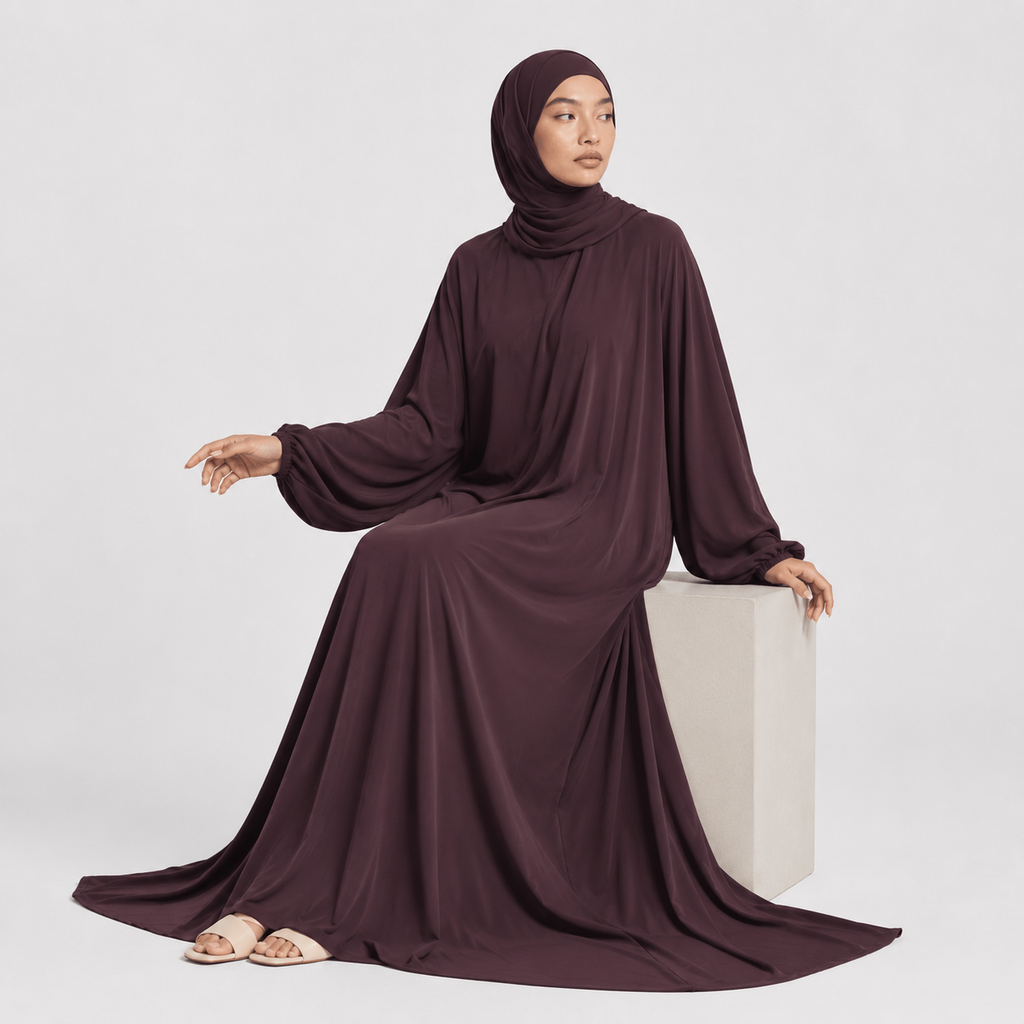 Woman wearing a dark brown hijab and dress on a white background