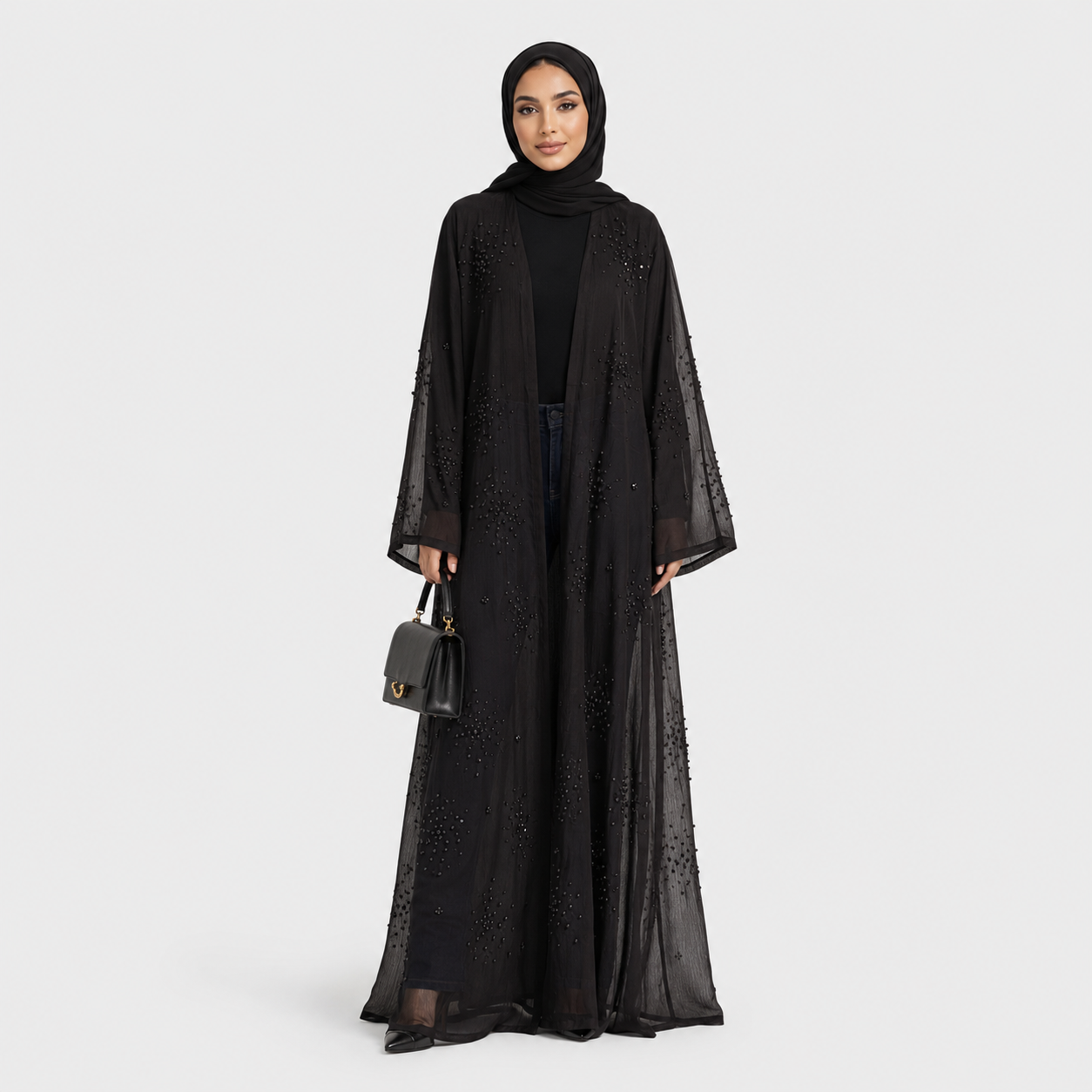 Woman wearing a black abaya with a matching hijab on a white background