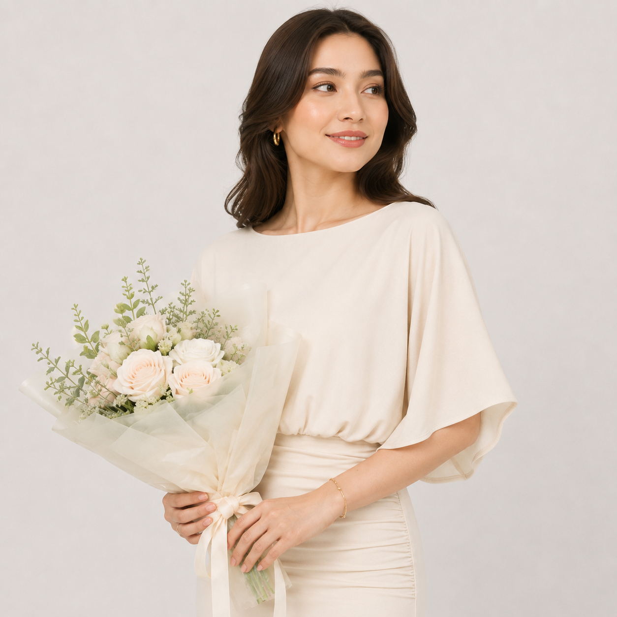 Woman in a white dress holding a bouquet of flowers against a plain background