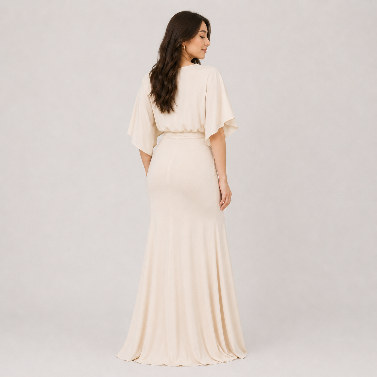 Woman wearing a long, light-colored dress against a plain background