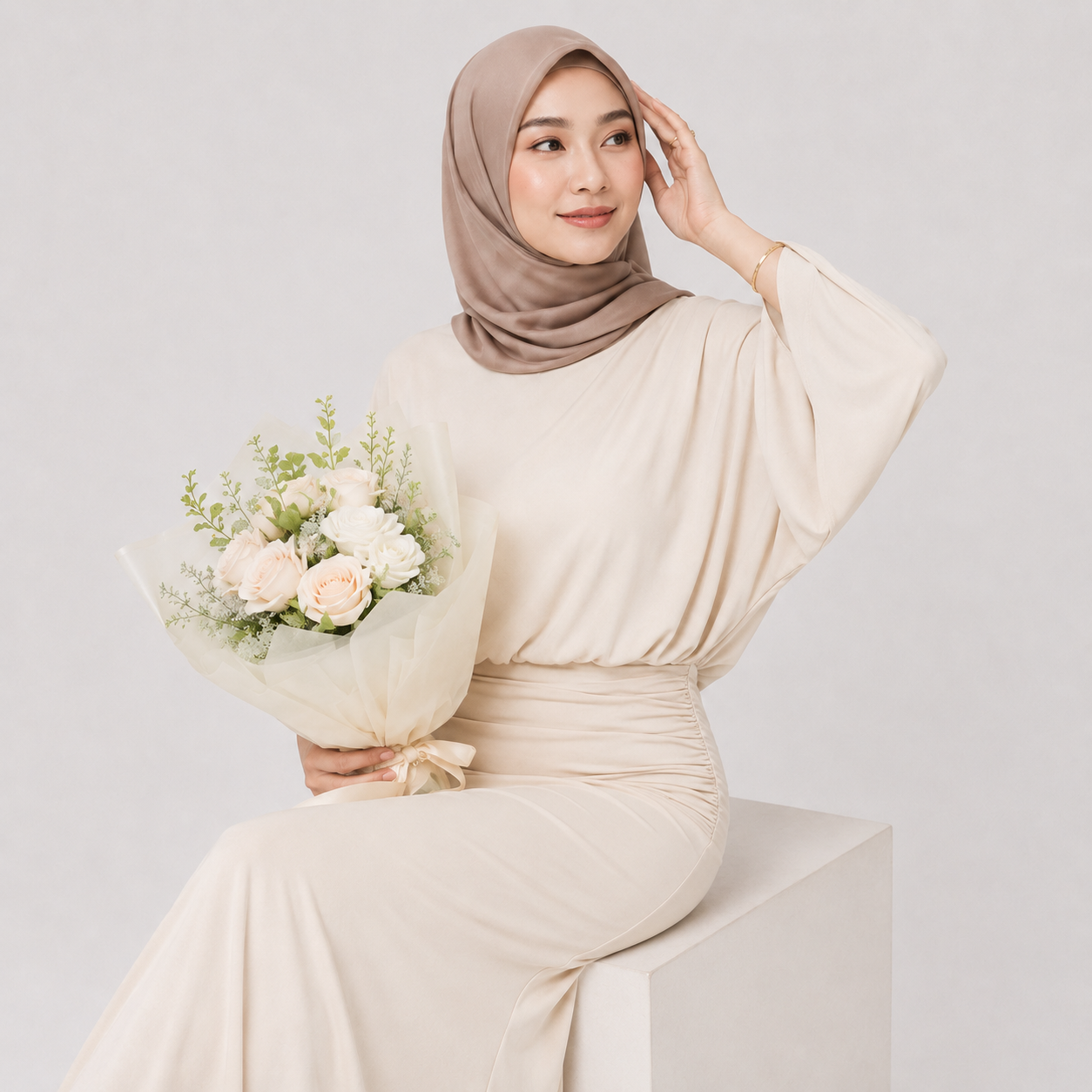 Woman in a beige outfit holding a bouquet of flowers against a light gray background