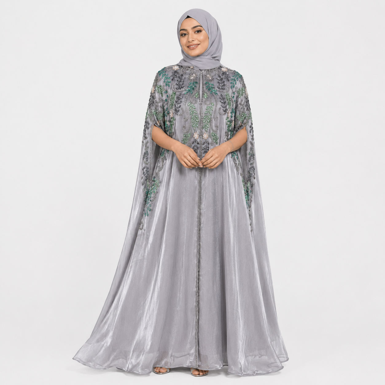 Woman wearing a gray embroidered dress with a matching hijab on a white background