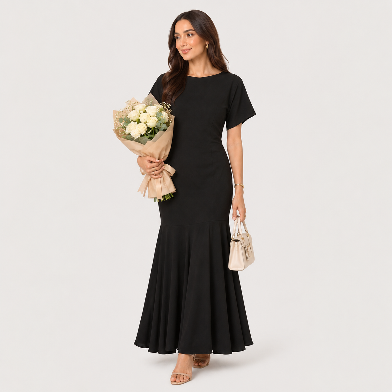 Woman in a black dress holding flowers and a handbag on a white background