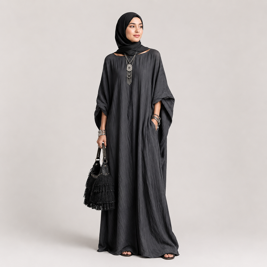 Woman wearing a long black dress and hijab on a light gray background