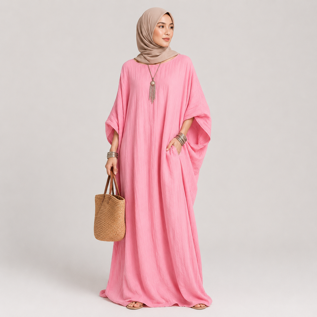 Woman wearing a pink dress holding a woven bag on a plain background