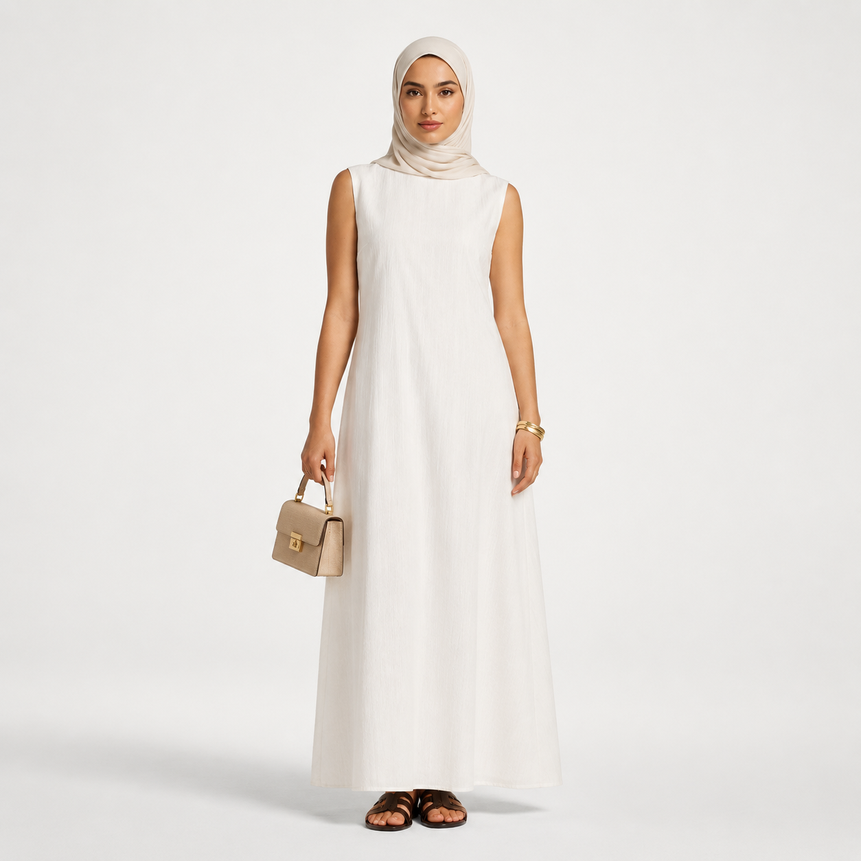 Woman wearing a white sleeveless dress holding a beige handbag on a light gray background