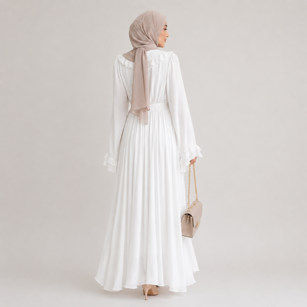 Woman wearing a long white dress and beige hijab on a plain background