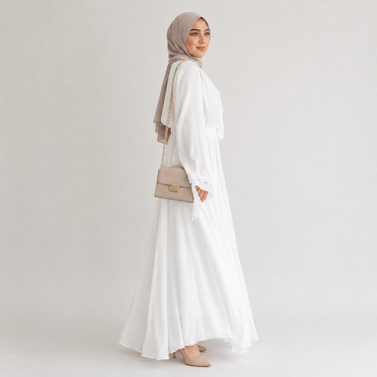 Woman wearing a white dress and beige hijab with a beige handbag on a light gray background