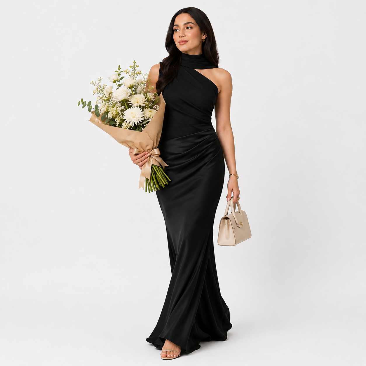 Woman in a black one-shoulder dress holding flowers and a clutch against a plain background