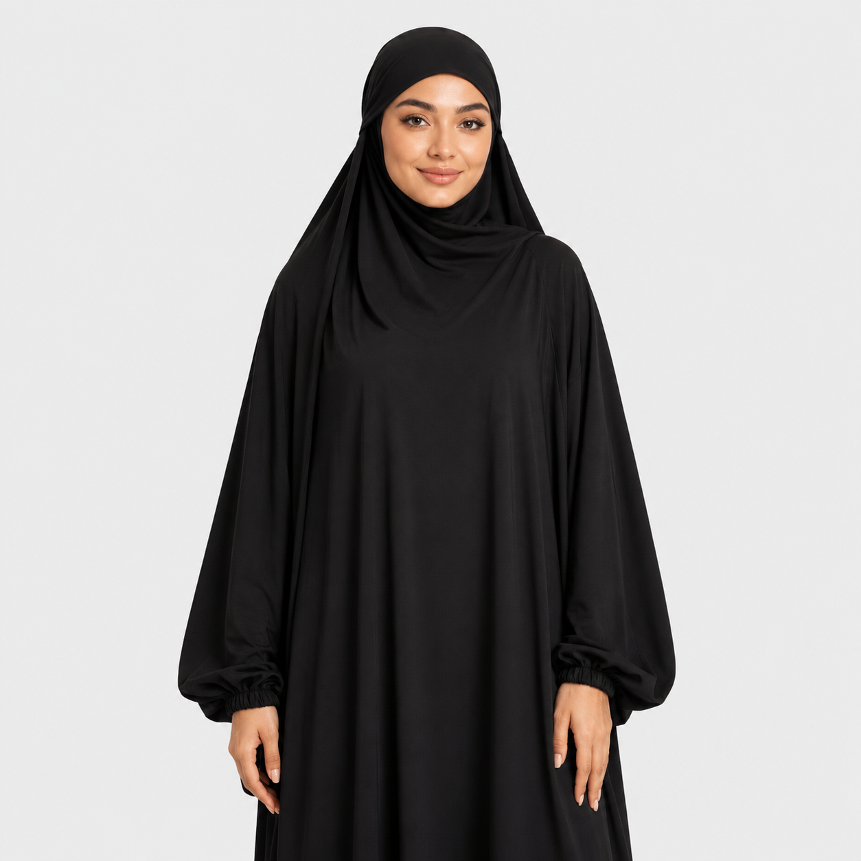 Woman wearing a black abaya and hijab on a white background
