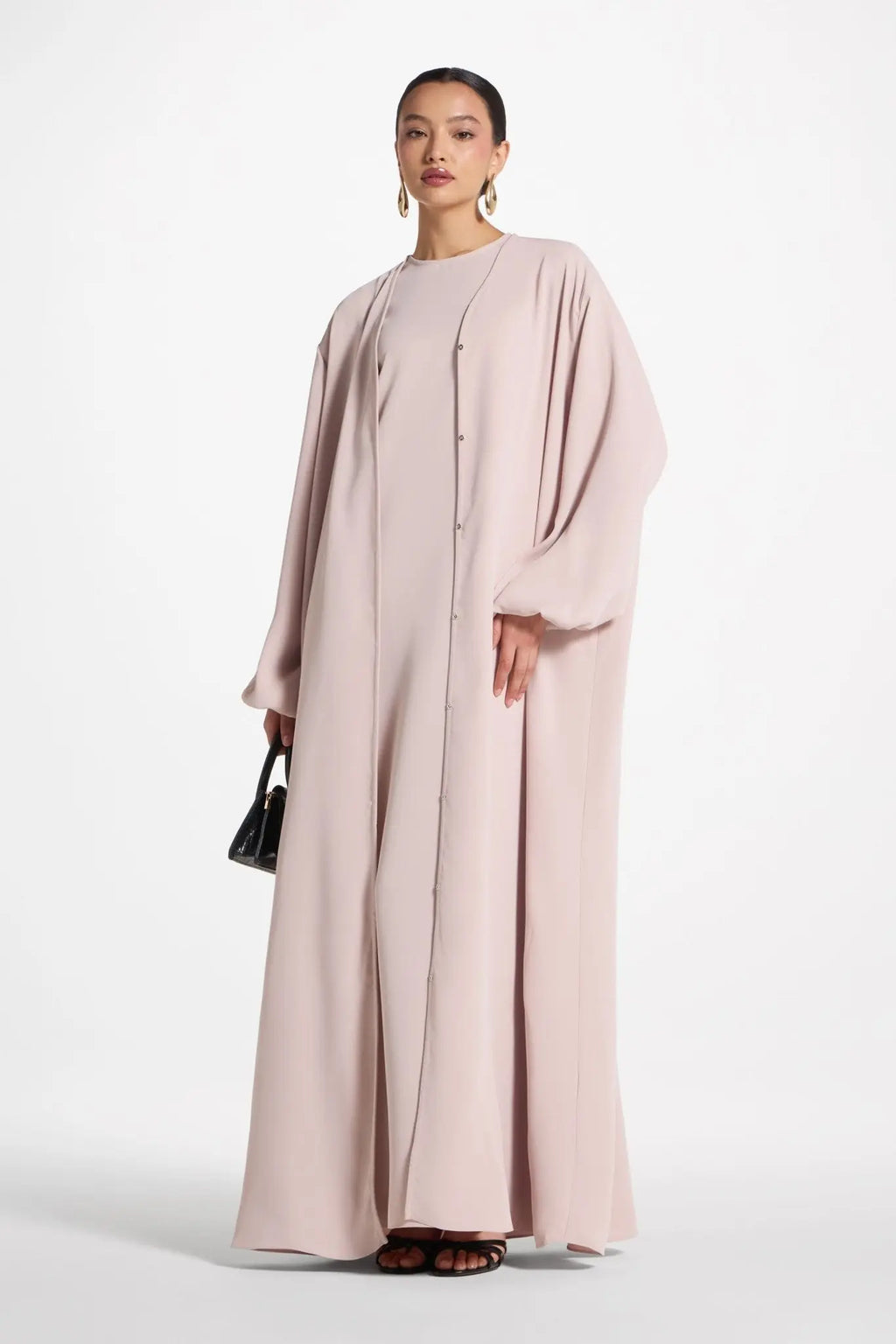 Woman wearing a light pink abaya on a white background