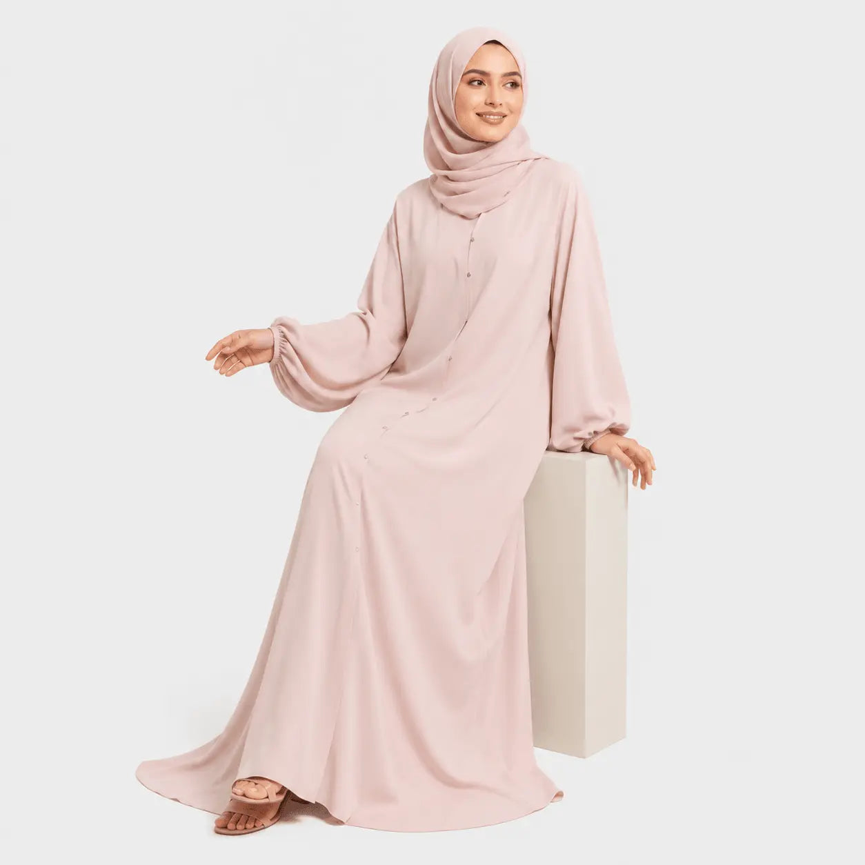 Woman wearing a pink abaya and hijab on a white background