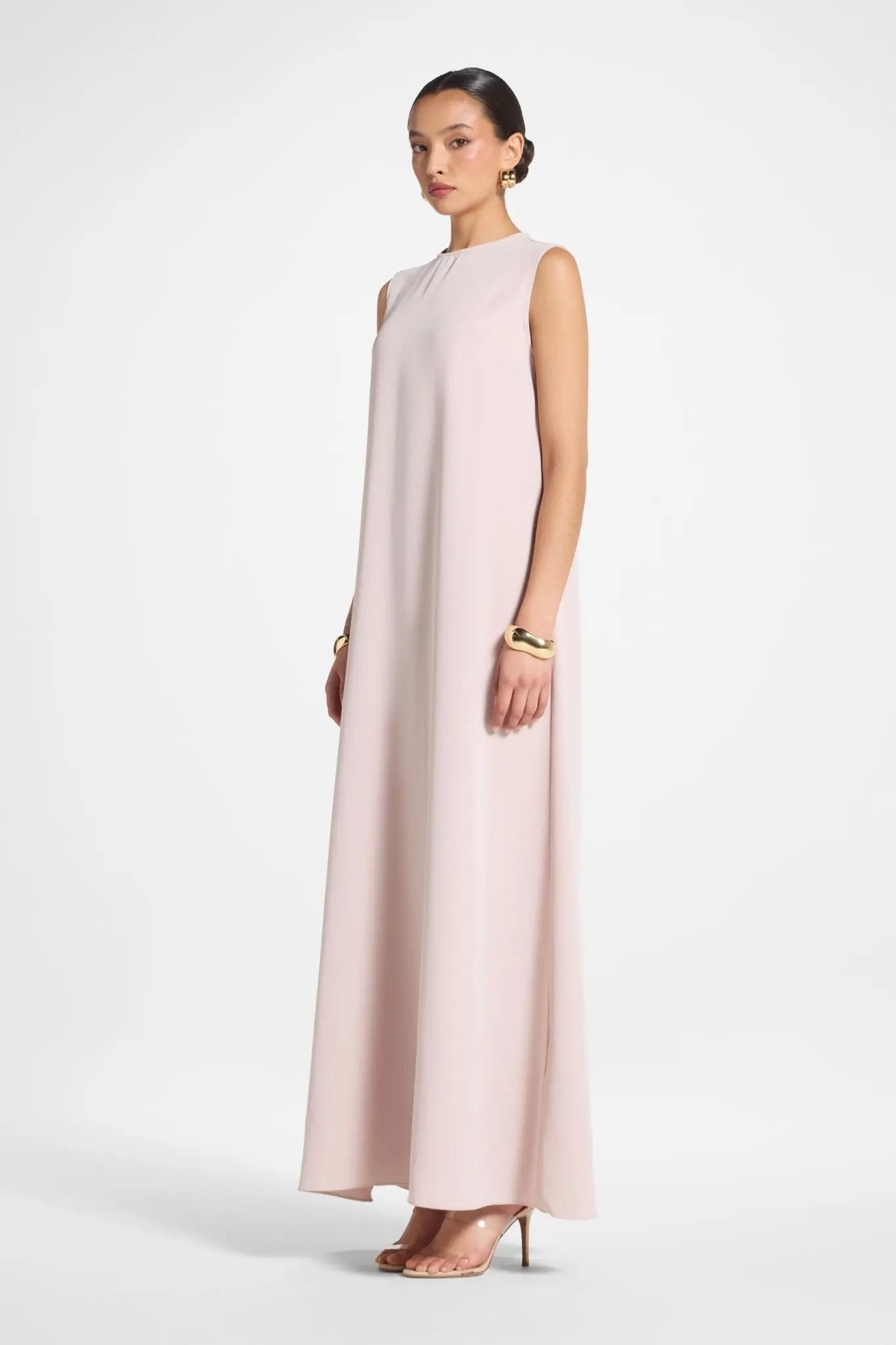 Woman wearing a light pink sleeveless dress on a white background