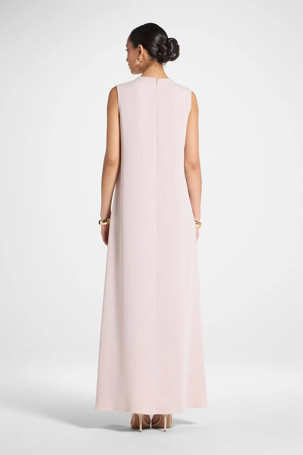 Woman wearing a long light pink dress on a white background