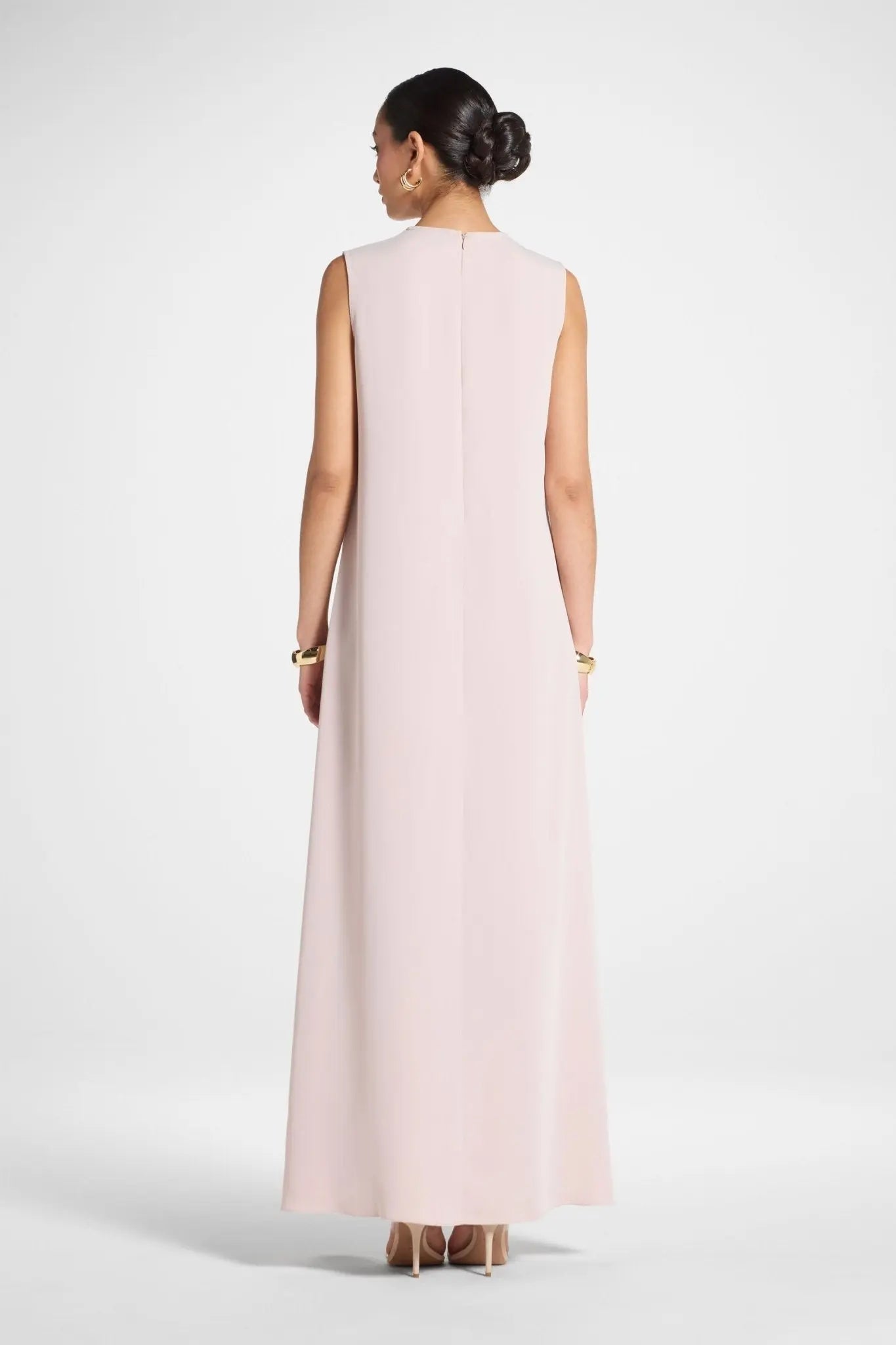 Woman wearing a long light pink dress on a white background