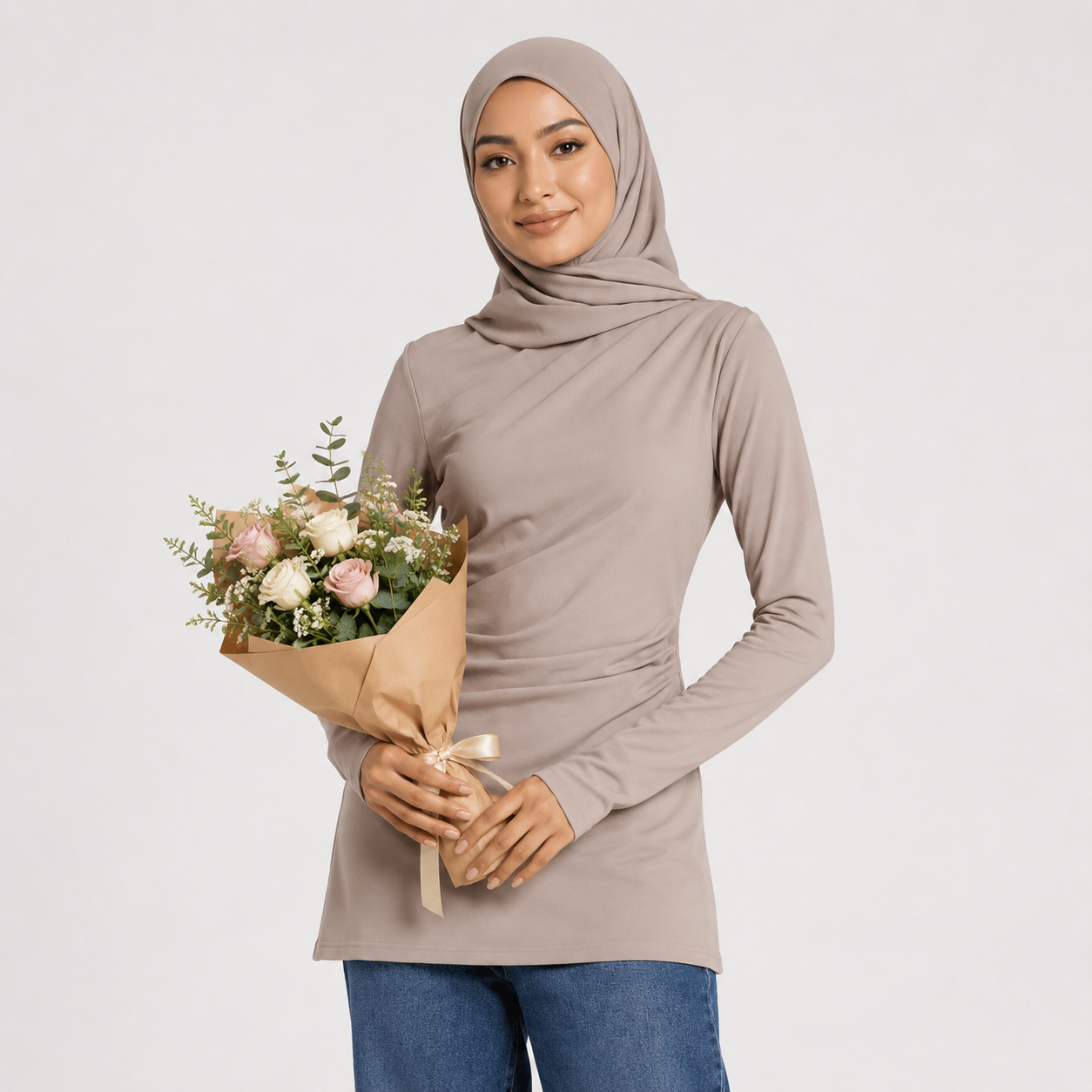Woman wearing a beige hijab and long-sleeve top, holding a bouquet of flowers against a white background