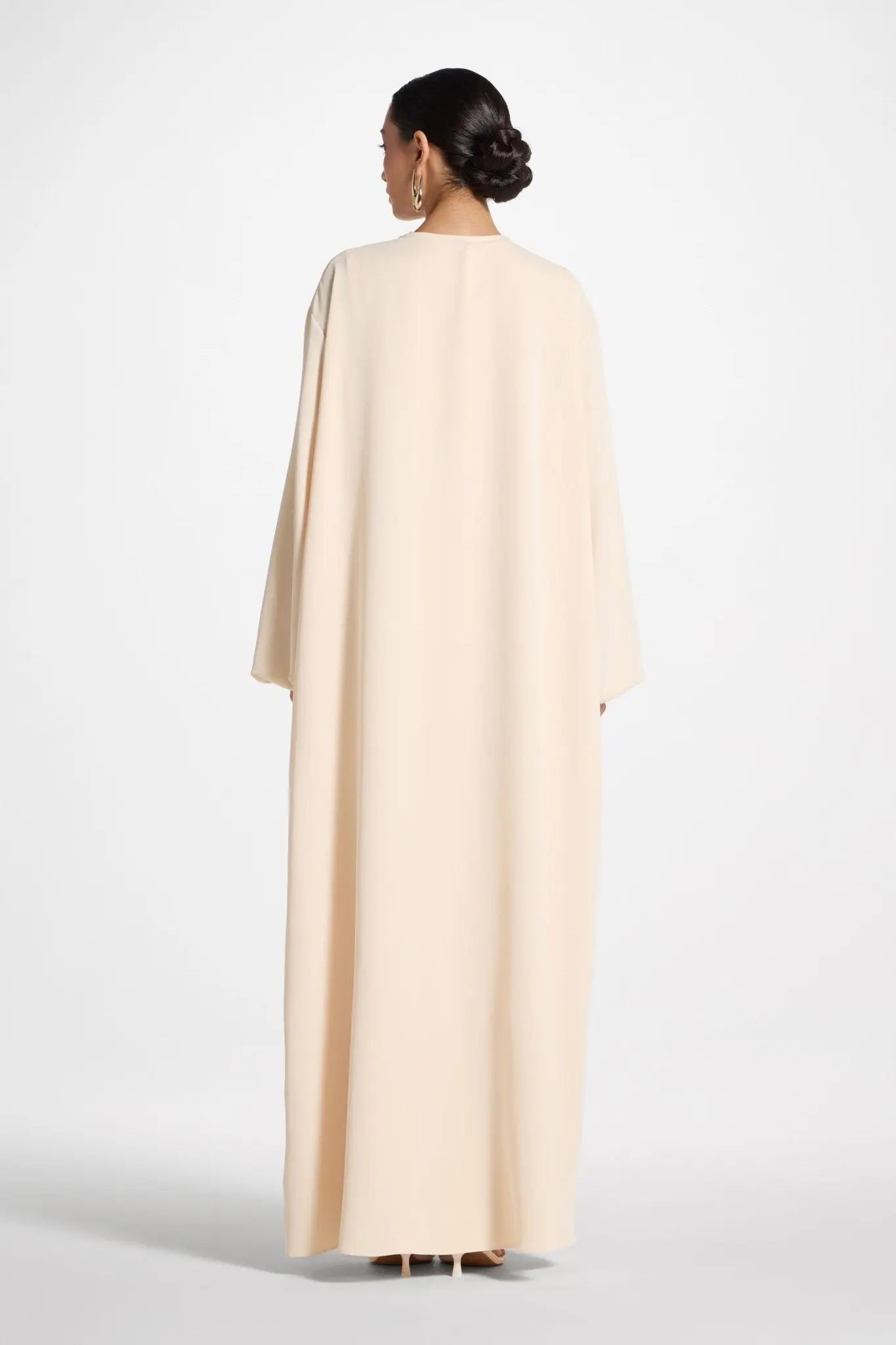 Woman wearing a beige cape on a white background