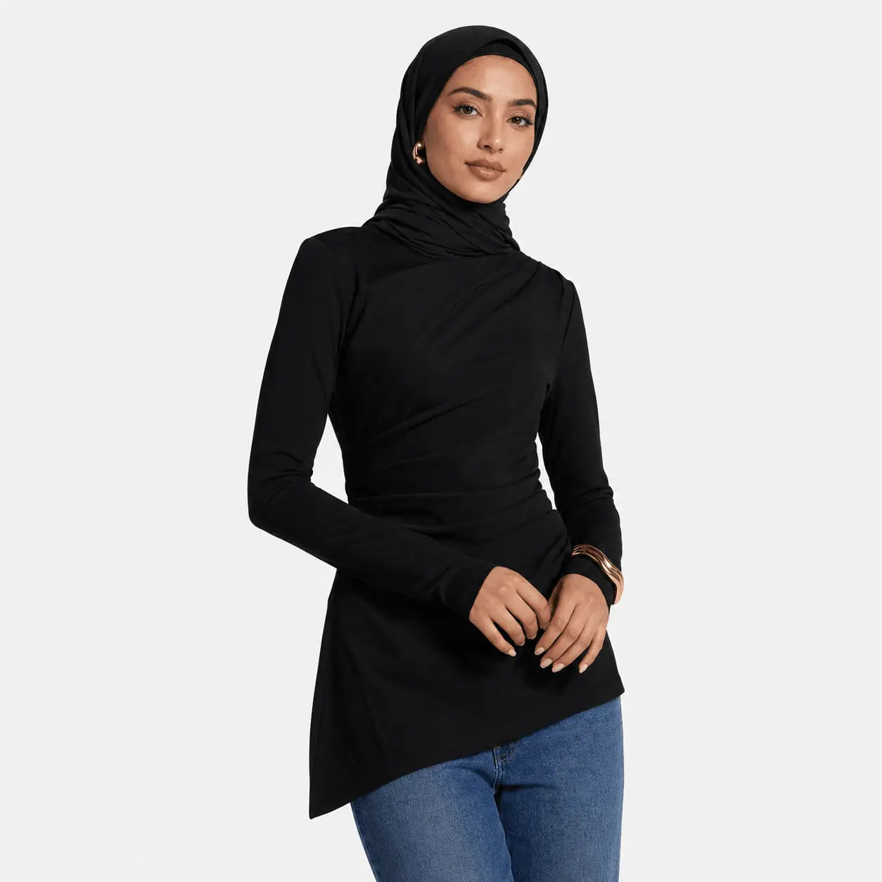 Woman wearing a black long-sleeve top and blue jeans on a white background