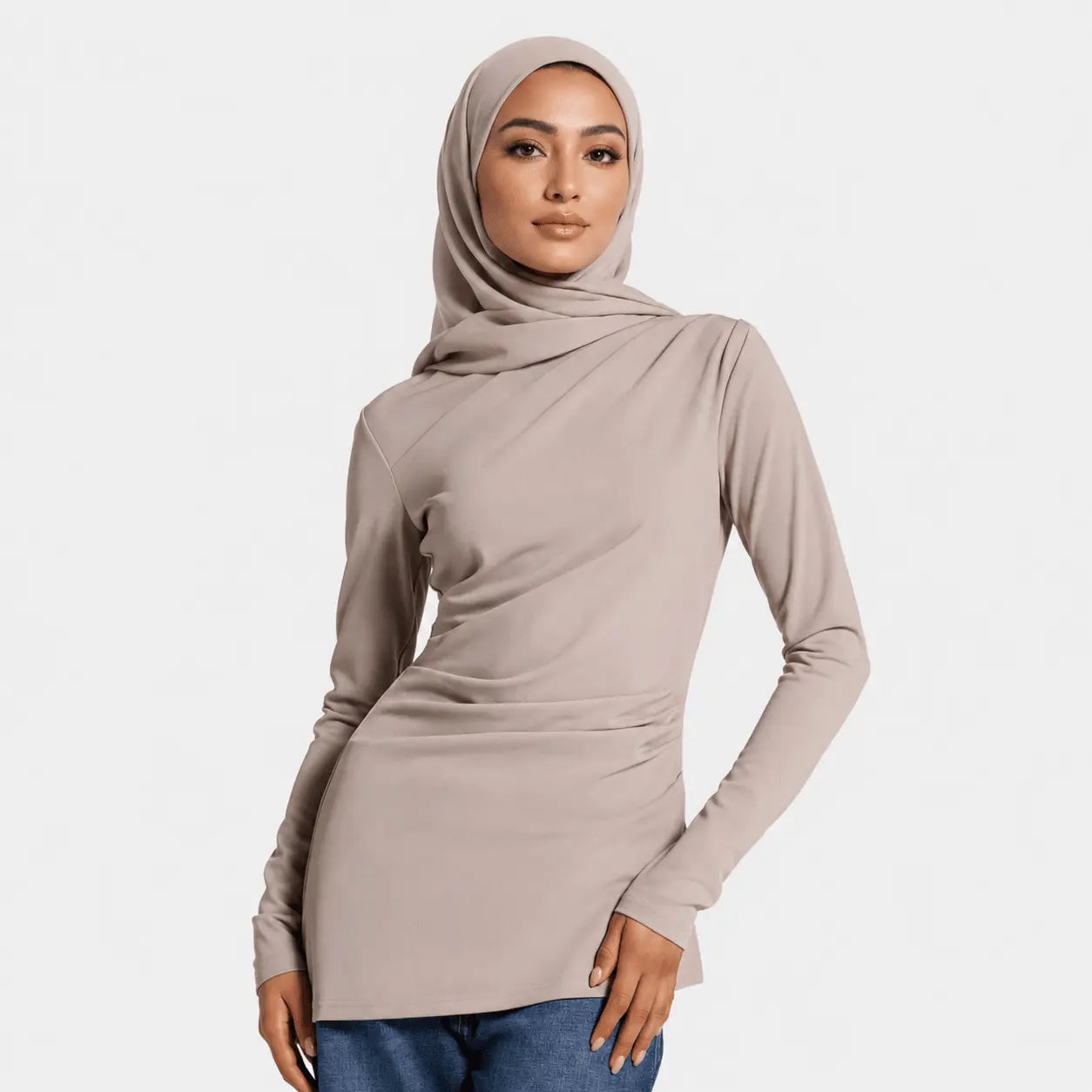 Woman wearing a beige long-sleeve top and hijab on a white background
