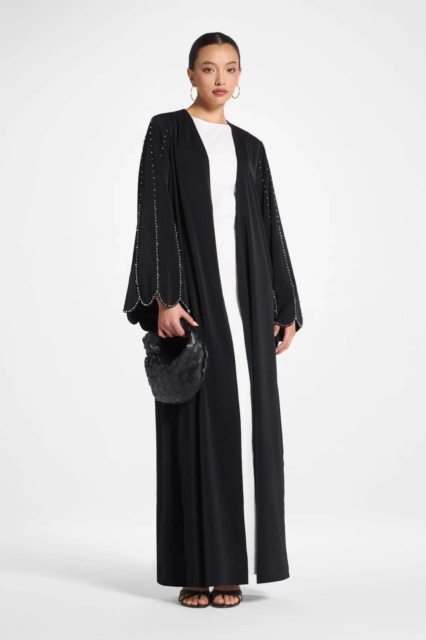 Woman wearing a black abaya with white top on a white background