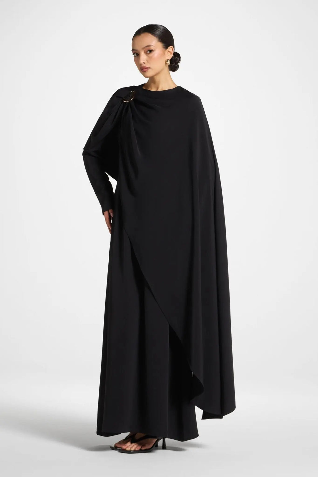 Woman wearing a black cape over a plain background