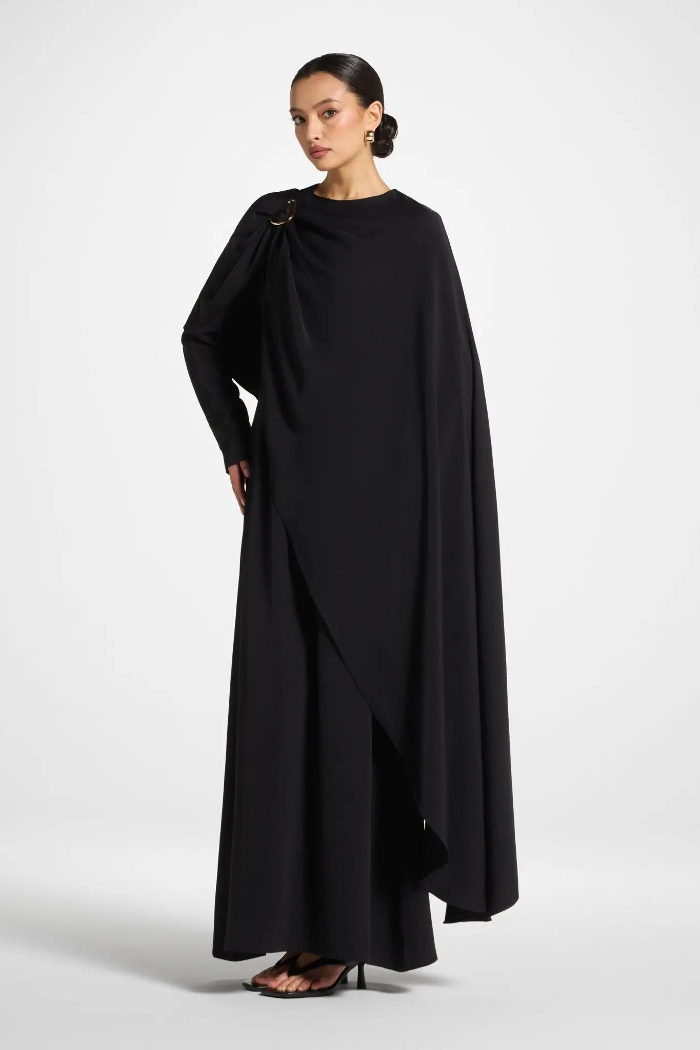 Woman wearing a black cape over a plain background