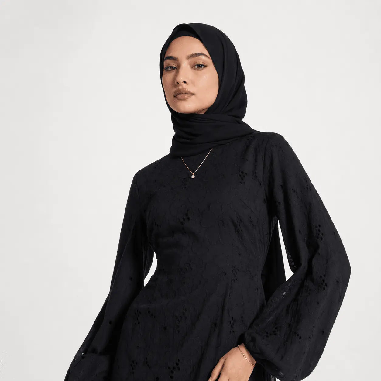 Woman in black hijab and elegant lace dress with balloon sleeves, minimalist style