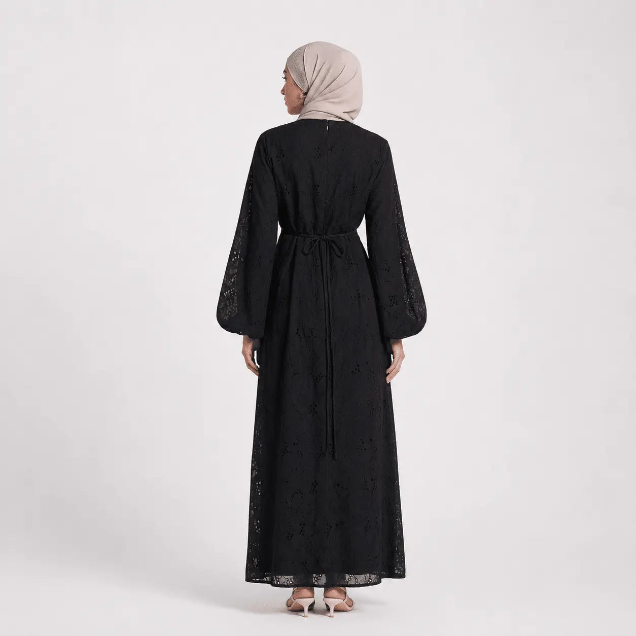 Black lace abaya with bell sleeves and tie waist, worn with hijab and heels