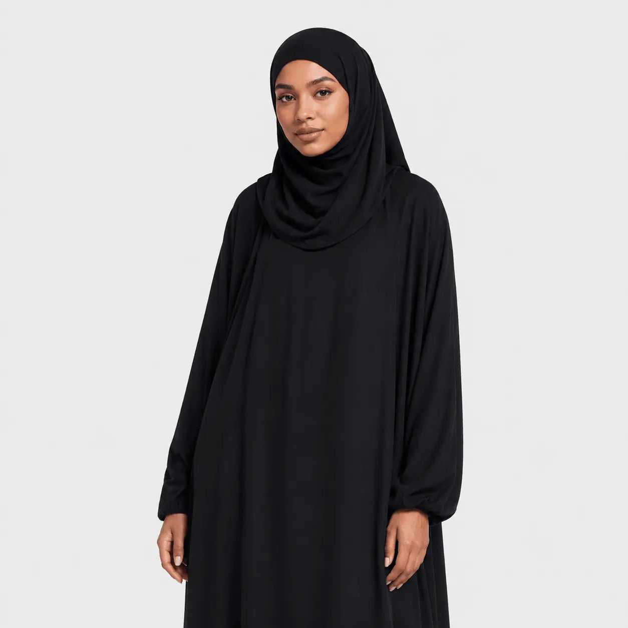 Woman wearing a black abaya and hijab on a white background