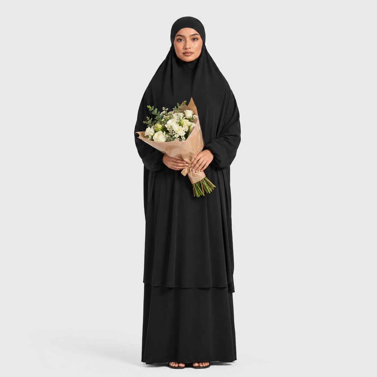 Woman in a black abaya holding a bouquet of flowers on a white background