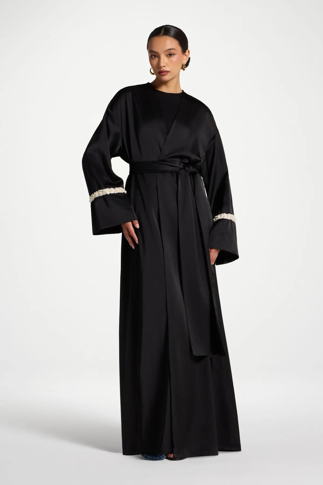 Woman wearing a black dress with white cuffs on a white background