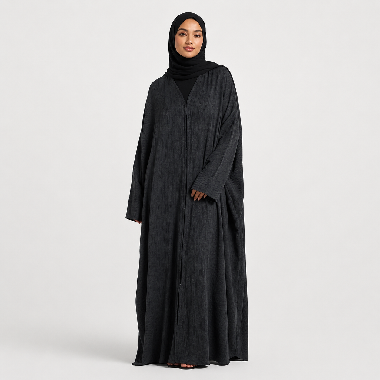 Woman wearing a black abaya and hijab on a white background